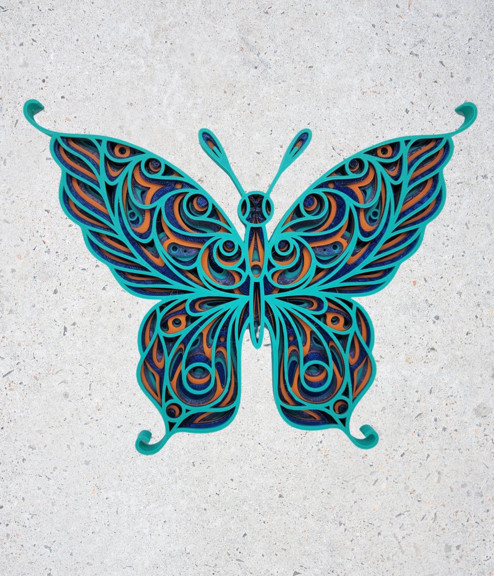A stylized butterfly made from layered, colorful paper strips arranged in intricate patterns on a light, speckled background.